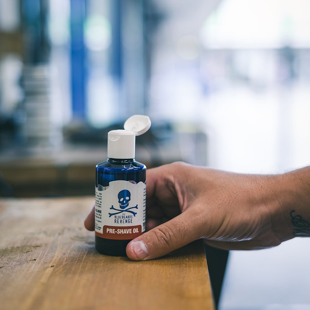 The Bluebeards Revenge Pre-Shave Oil being picked up by a man's hand in a barbershop